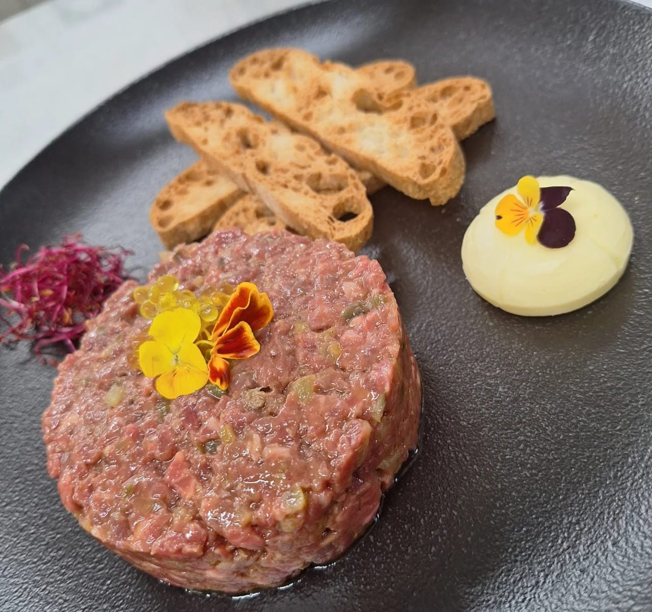 🥩🔥 L’STEAK TÀRTAR AMB EL TOC ÚNIC DEL XEF JORDI GUERRERO! 🔥🍽️   A KRAM Restaurant, la passió per la gastronomia exquisida es reflecteix en cada plat, i el nostre Steak Tàrtar és la millor prova d’això.   ✨ Elaborat amb la mestria del xef Jordi Guerrero, aquest plat és una combinació perfecta de textura, intensitat i matisos que conquereix els paladars més exigents.   🍷 Gaudeix-lo al centre d’Andorra en un ambient exclusiu! La carn madurada, el punt just d’adob i la presentació impecable fan del nostre Steak Tàrtar una autèntica obra d’art gastronòmica.   📍 Reserva la teva taula i descobreix una experiència única!   🔸 #KramRestaurant #SteakTàrtar #JordiGuerrero #SaborAutèntic #GastronomiaPremium #AltaCuina #MenjarQueSedueix #CentreDAndorra #RestaurantAndorralaVella #AndorralavellaRestaurant #cuinaAndorrana #Carnsmadurades #Cuinadeproximitat #centrecomercialandorralaVella #lesmillorscarns #XefJordiGuerrero  😊✨🔥  