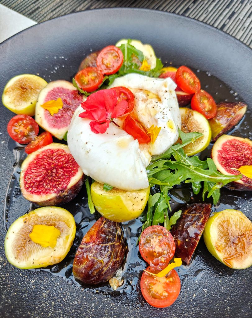 Amanida de figues de coll de dama amb burrata Del mar a la terra, amb elegància. A KRAM, la millor marisqueria d’Andorra la Vella, també celebrem els sabors frescos i delicats de la terra. Et presentem la nostra amanida de figues de coll de dama blanques i vermelles amb burrata: una combinació que uneix la dolçor de la fruita amb la cremositat d’un formatge amb història. La burrata, formatge de llet de vaca originari de la regió italiana de la Pulla, va ser inventada a la ciutat d’Àndria. La seva textura suau i el seu cor cremós fan d’aquesta amanida una experiència única. I de la subtil vinagreta només podem dir que és única. Figues fresques, contrastos subtils i un toc mediterrani que et sorprendrà. Vine a tastar-la a KRAM, on cada plat és una declaració de sabor. #RestaurantKRAM #AndorraLaVella #MarisqueriaKRAM #Burrata #FiguesDeCollDeDama #CuinaMediterrània #GastronomiaAndorrana #CuinaDeTemporada #FoodieAndorra #AmanidaGourmet #SaborsQueEnamoren #AndorraGourmet #PlatAmbHistòria #CuinaCreativa #ExperiènciaKRAM #DelíciesDeLaTerra
